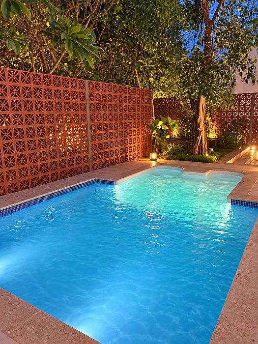 Evening-lit jacuzzi pool with jaali wall by Moothedan